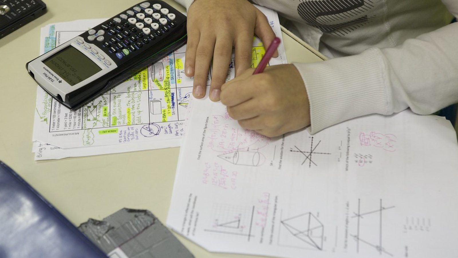 A plain black calculator and a small stack of blank white price tags on an off-white surface
