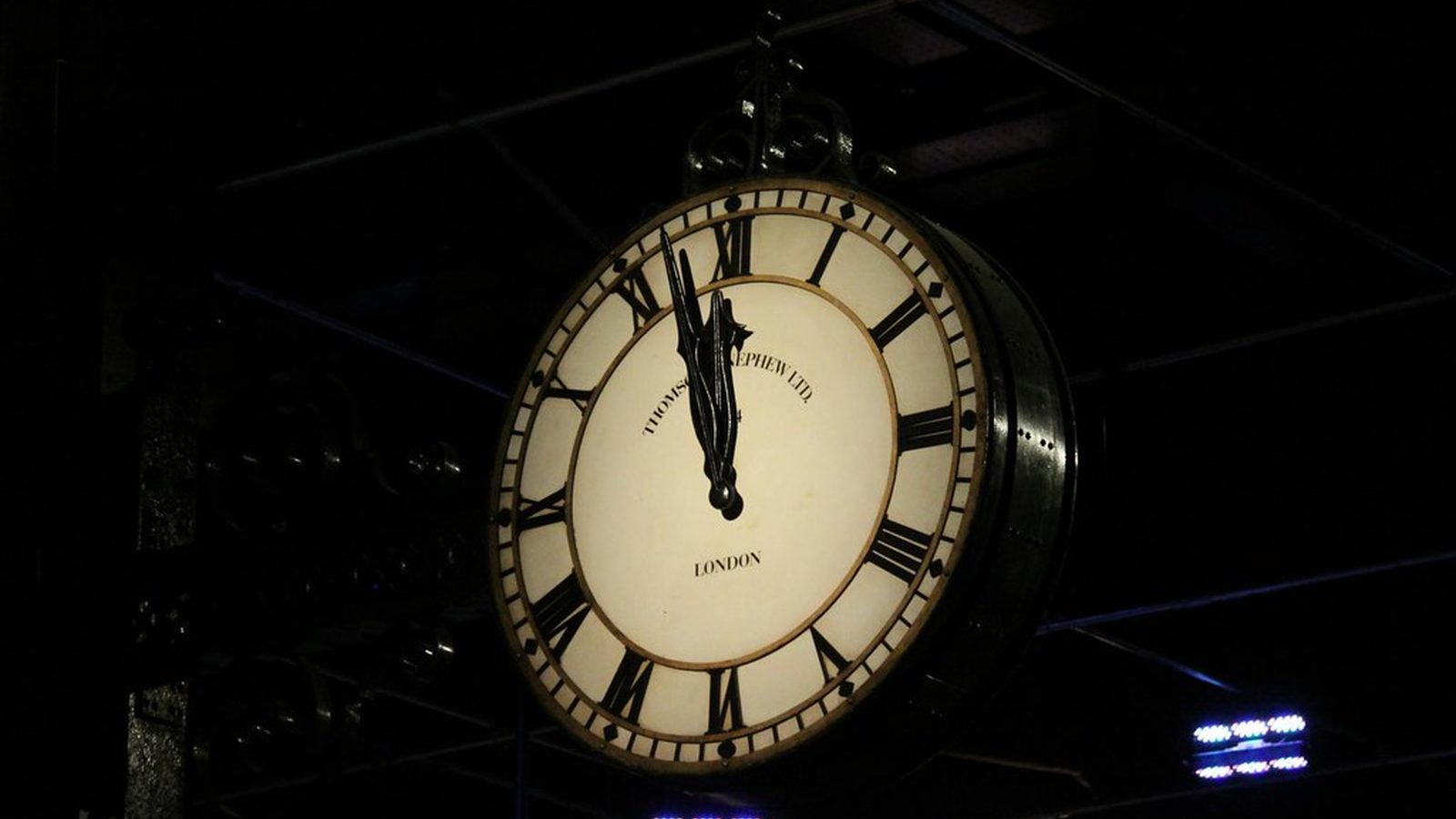 Three plain white analog wall clocks showing different positions on a slate grey wall